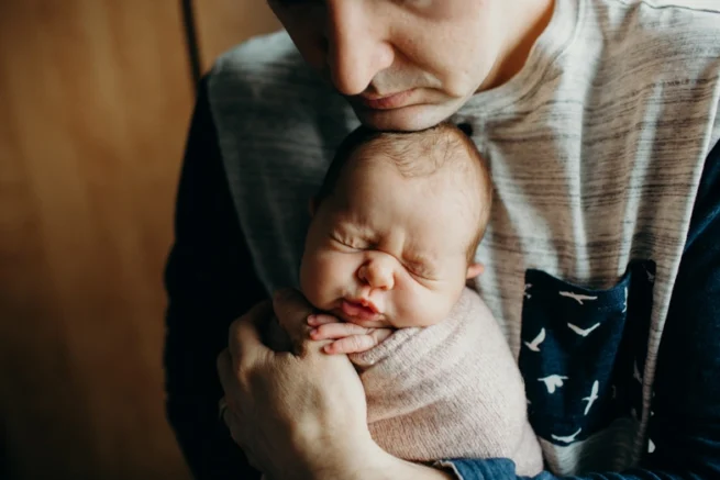 Nouveau-né blotti dans les bras de son père, photo spontanée par photographe à Rimouski