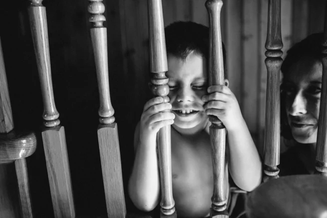 Petit garçon observant à travers une barrière, portrait documentaire noir et blanc haute résolution à Rimouski