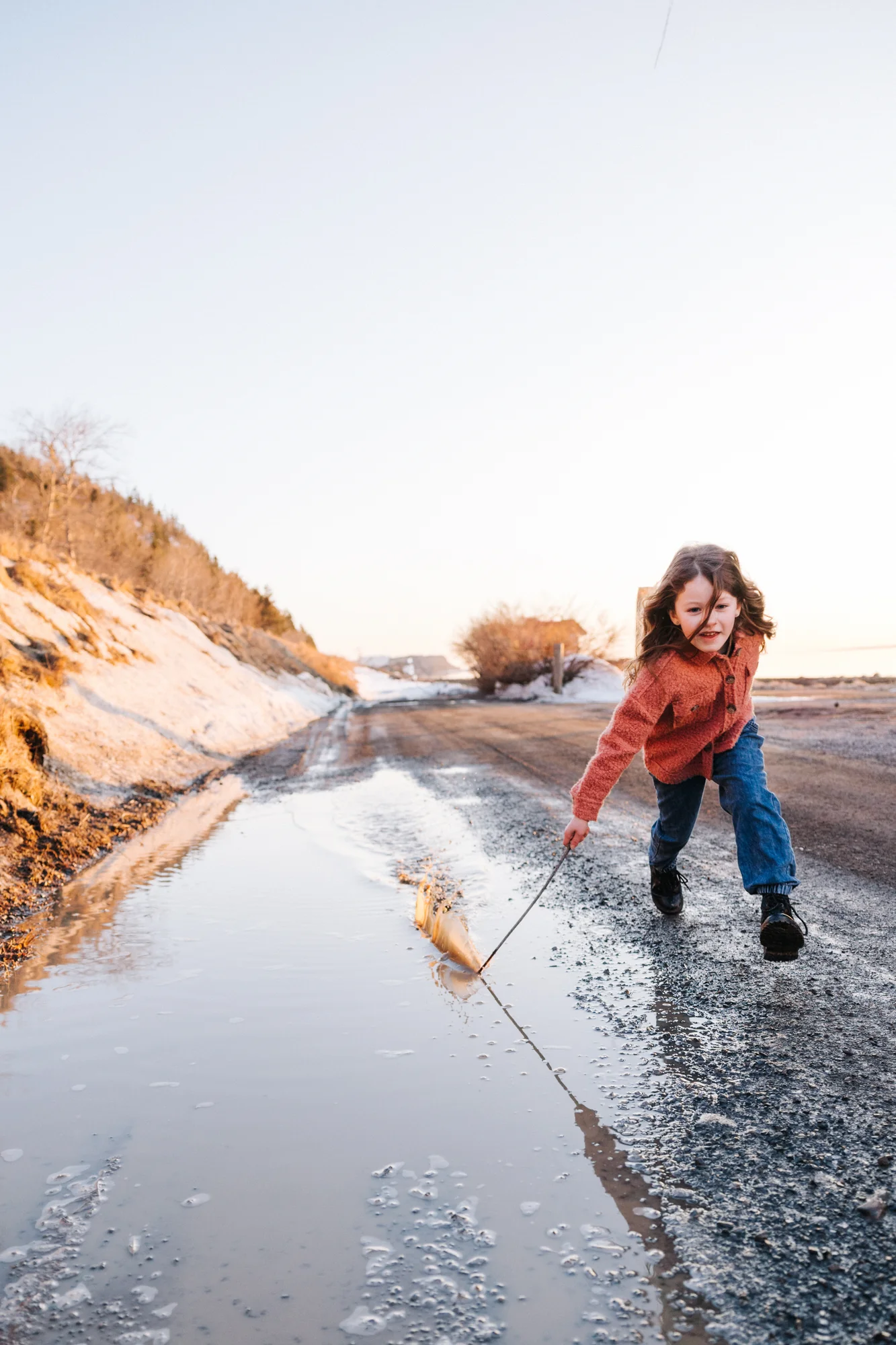 L'instant vrai : une petite fille s'amuse dans une flaque d'eau, capturée par votre photographe de famille à Rimouski.