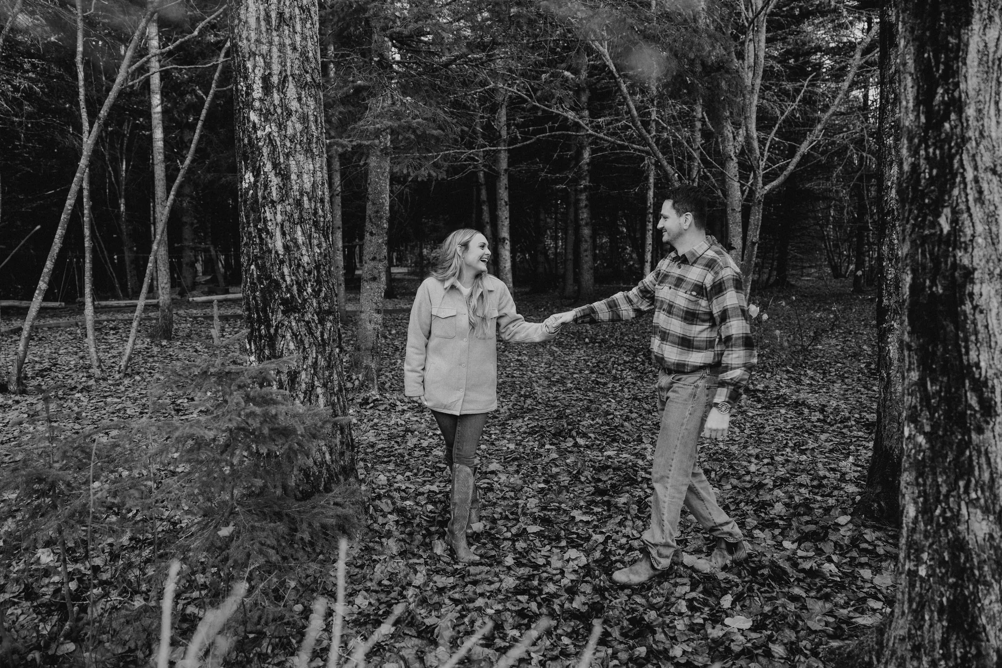 Moment secret entre deux amoureux sous les sapins en noir et blanc.