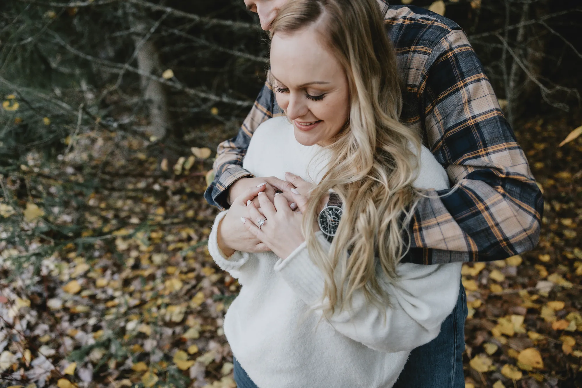 Couple se serrant fort pour se réchauffer sous les arbres.