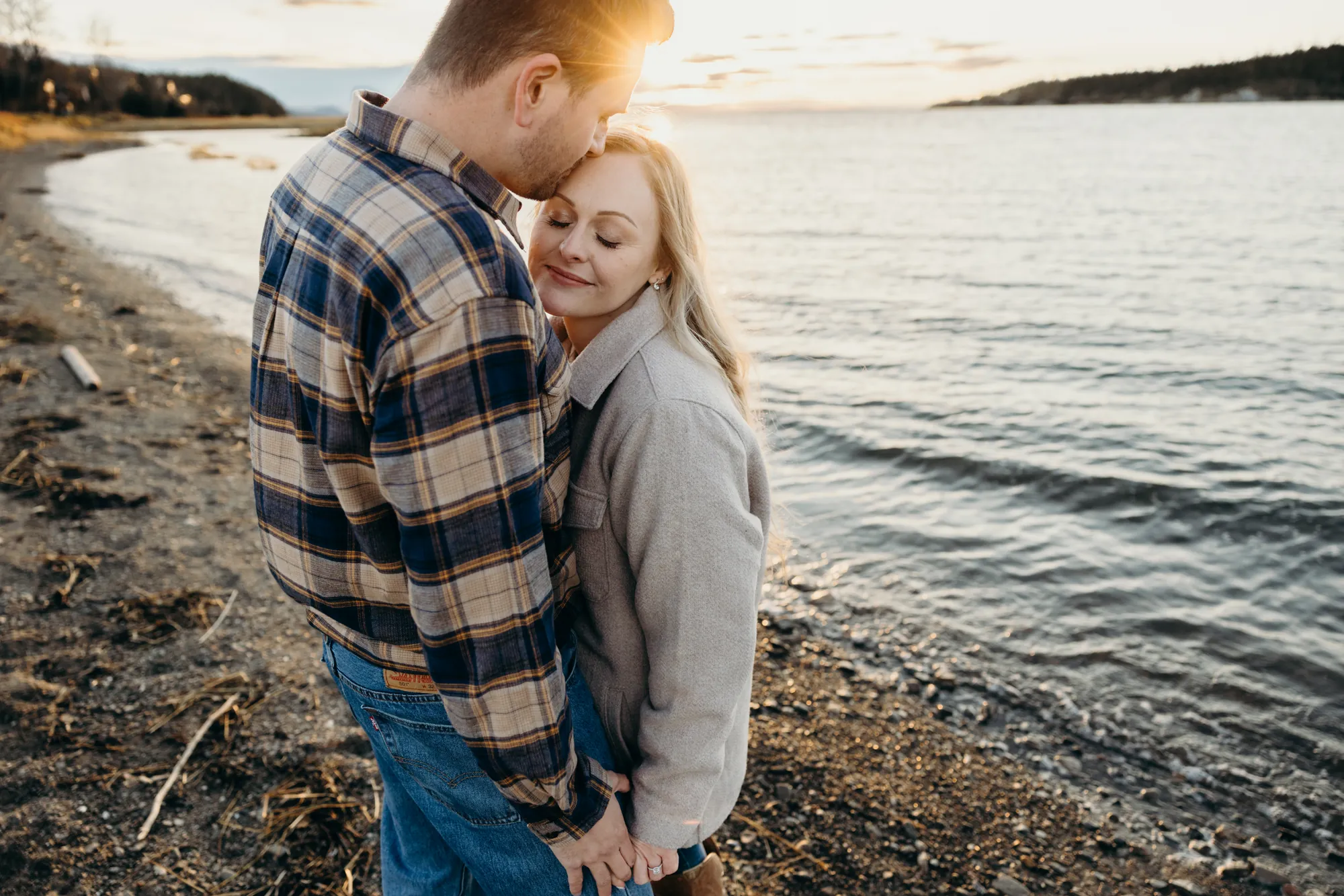Guillaume embrassant le front de sa conjointe devant le fleuve.