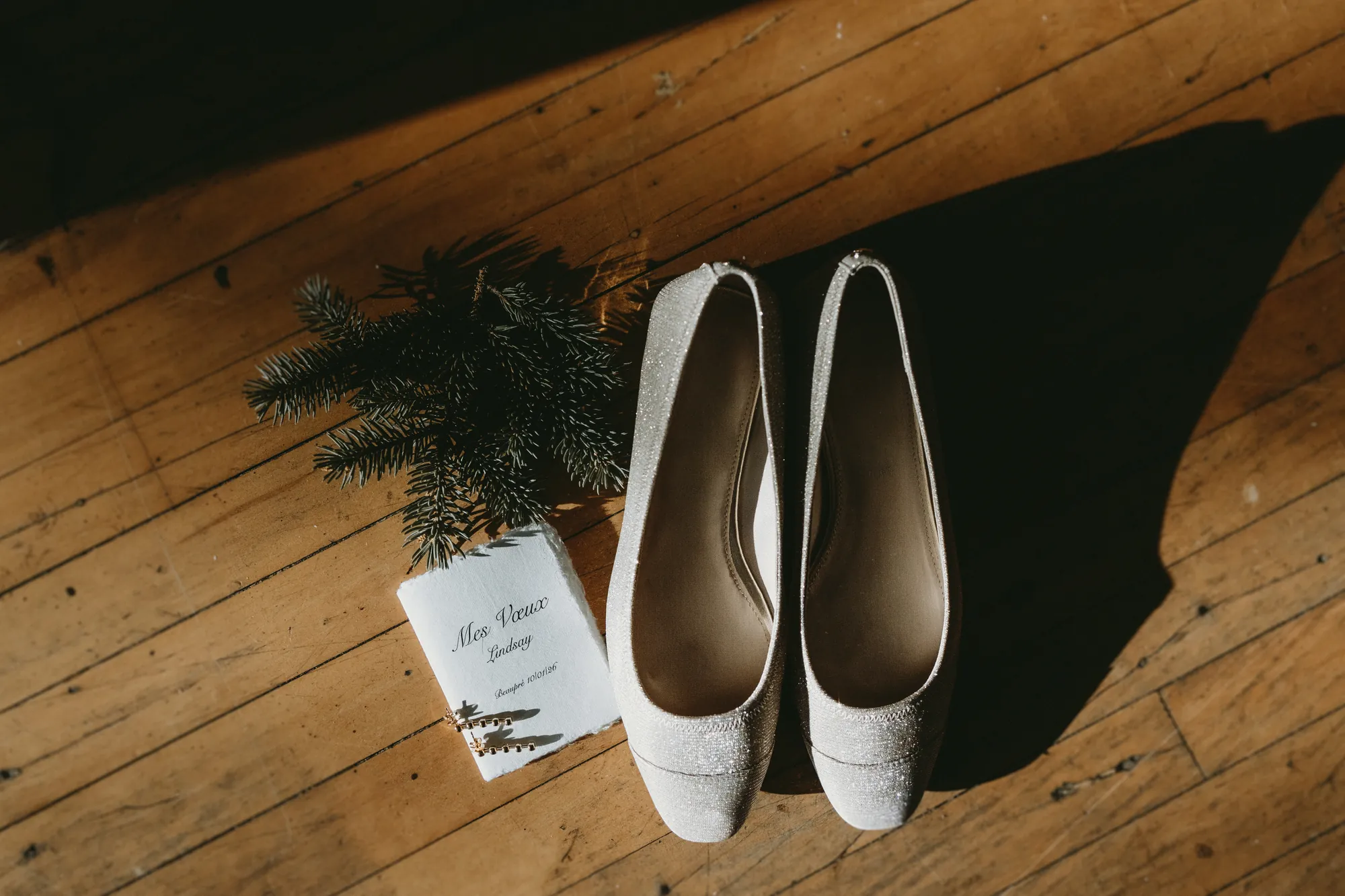 Chaussures de mariée blanches déposées au sol à côté du programme de la journée.