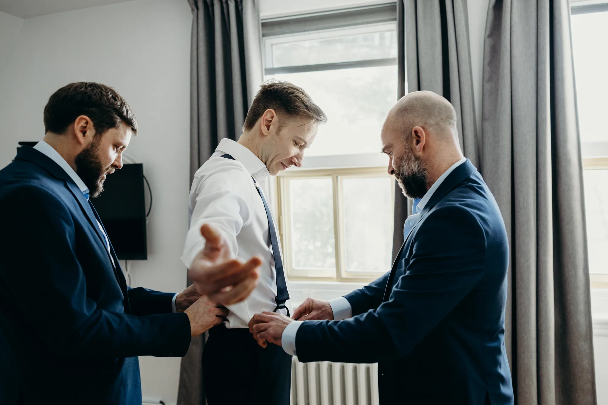 Marié qui se fait habillé par ses garçons d'honneur.