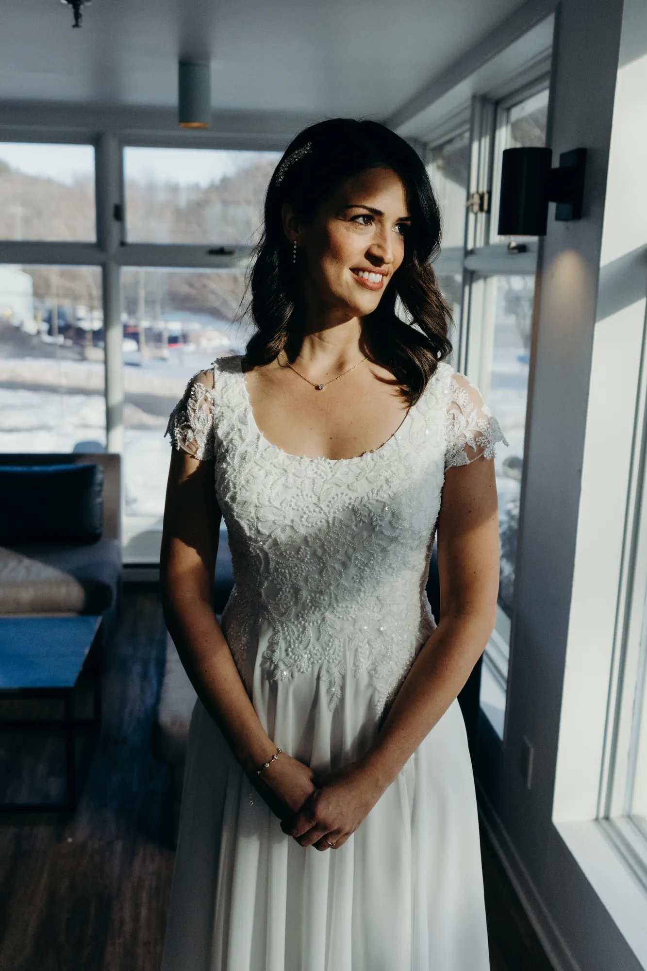 Mariée Lindsay regardant par la fenêtre de sa suite nuptiale au Manoir St-Anne.