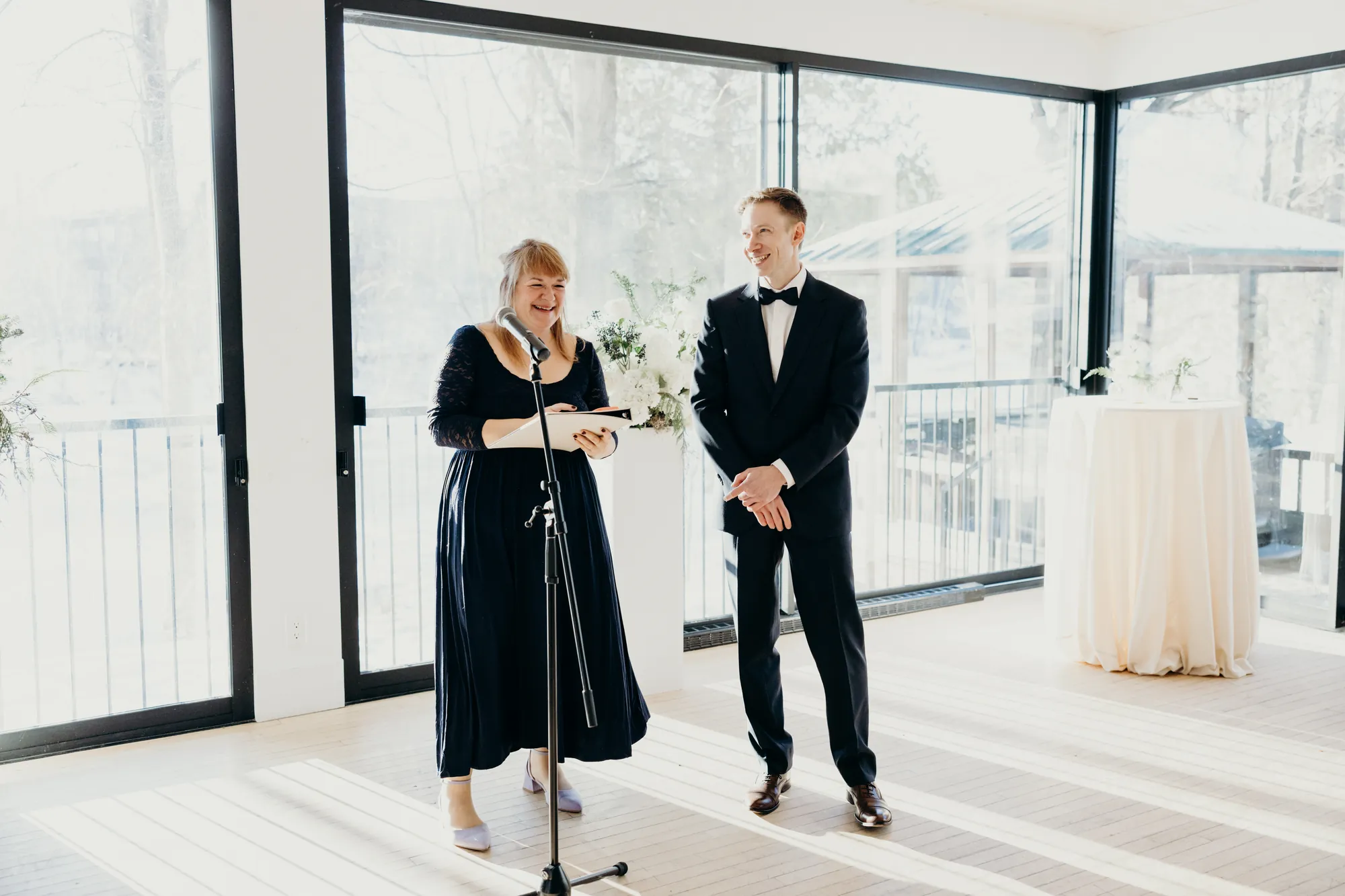 La célébrante s'adressant aux mariés devant les grandes baies vitrées du Manoir.