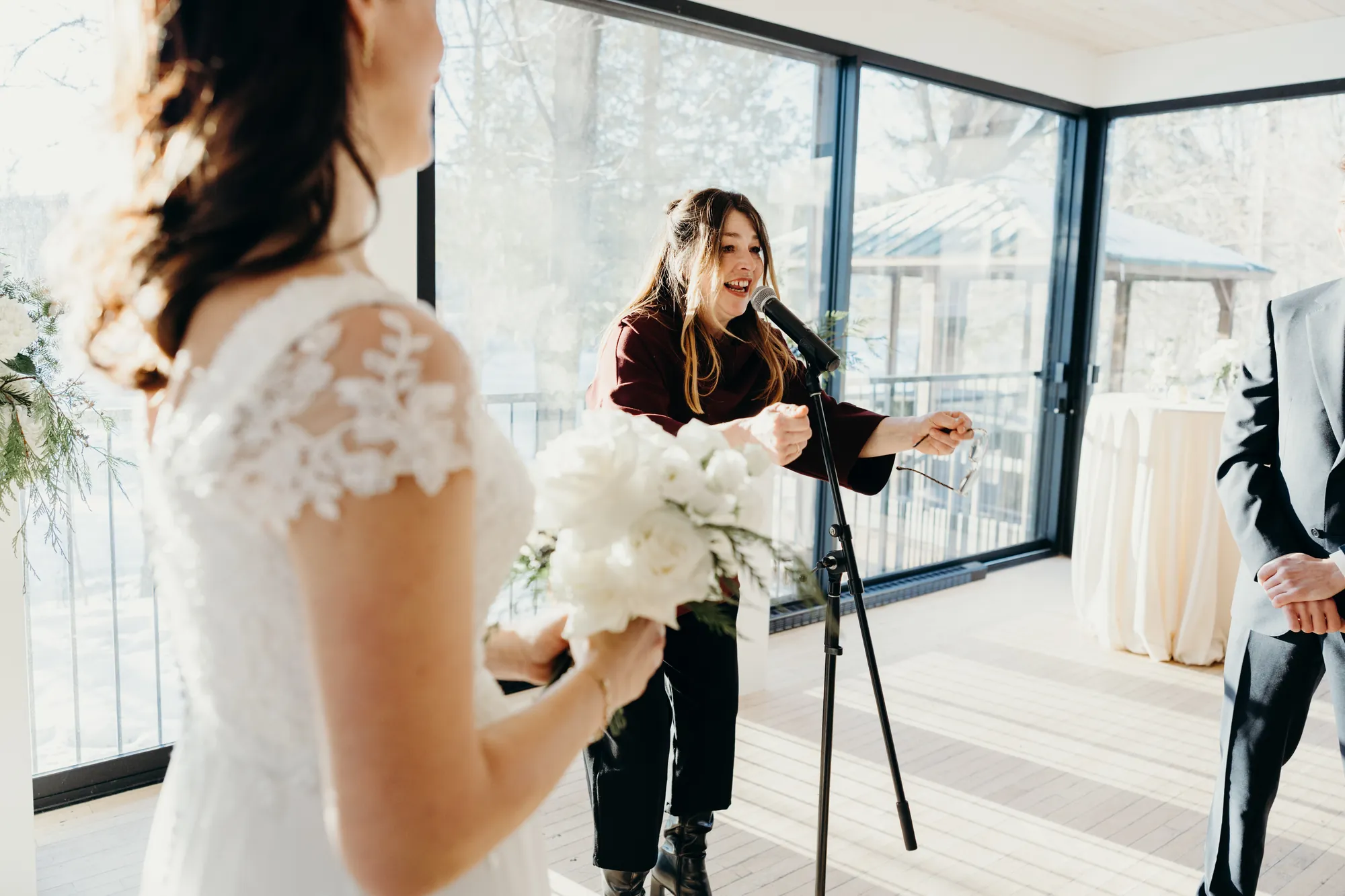 Mariée tenant son bouquet blanc devant l'autel baigné de lumière naturelle.