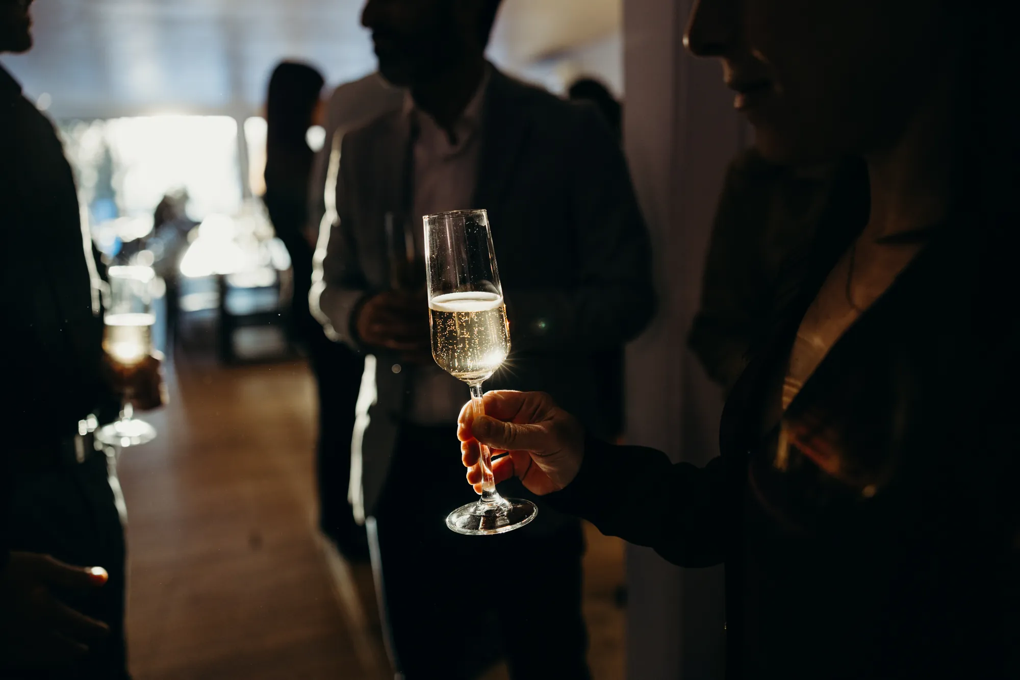 Main d'un invité tenant une flûte de champagne lors du cocktail de mariage à Beaupré.