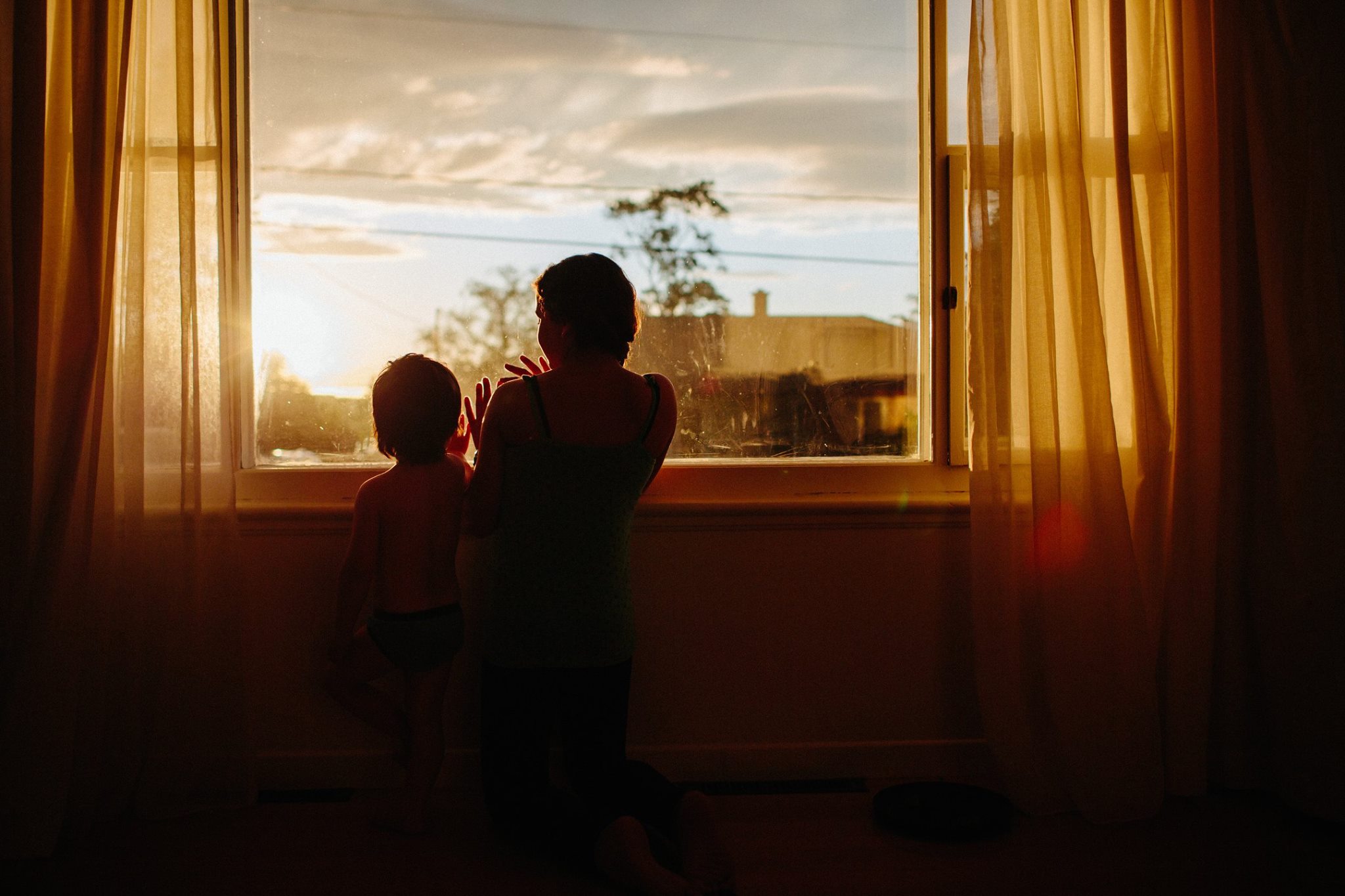 Silhouette contemplative de ma fille Morganne et son frère Mihiikin devant une fenêtre au Bic, illustrant le début de la carrière professionnelle de 5Mphotographie à Rimouski.