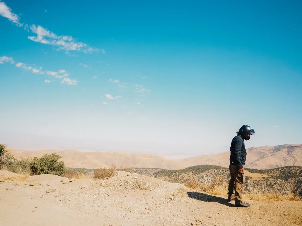 Martin qui regarde en bas d'un falaise lors d'un voyage en moto évasion. 