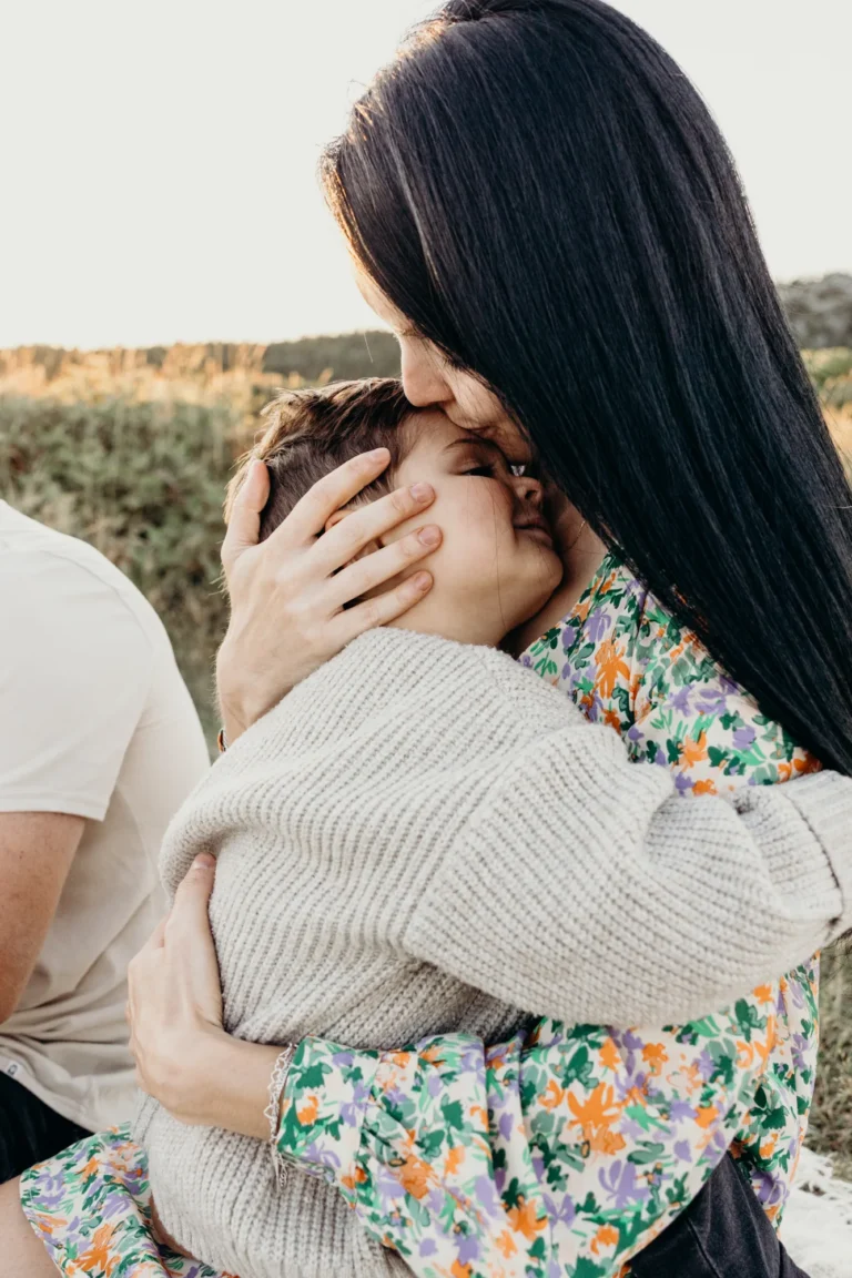 Mère qui embrasse le front de son fils dans ses bras.