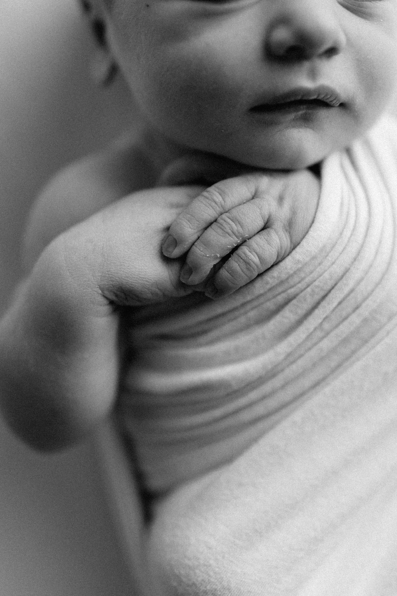 Détail en noir et blanc de la petite main de Noam posée sur son épaule, photographie macro par une photographe de Rimouski. 