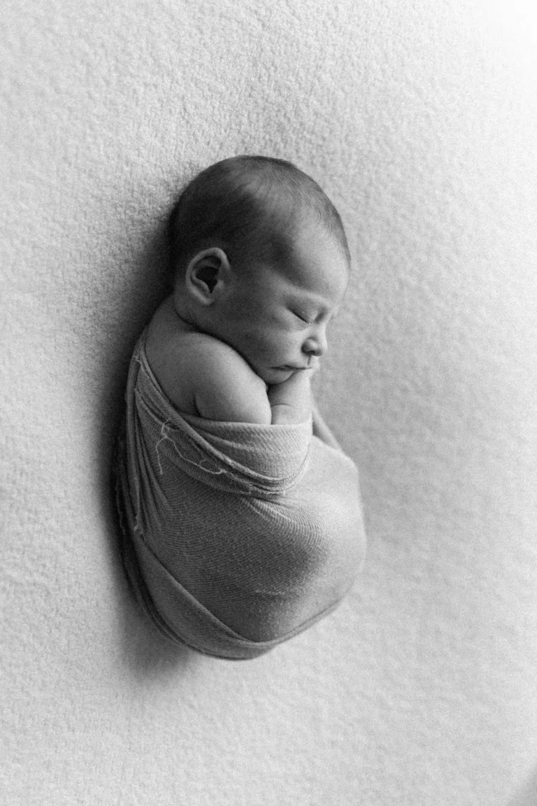 Bébé Marc-Edouard sur le dos, emmaillotage blanc minimaliste au studio mobile.