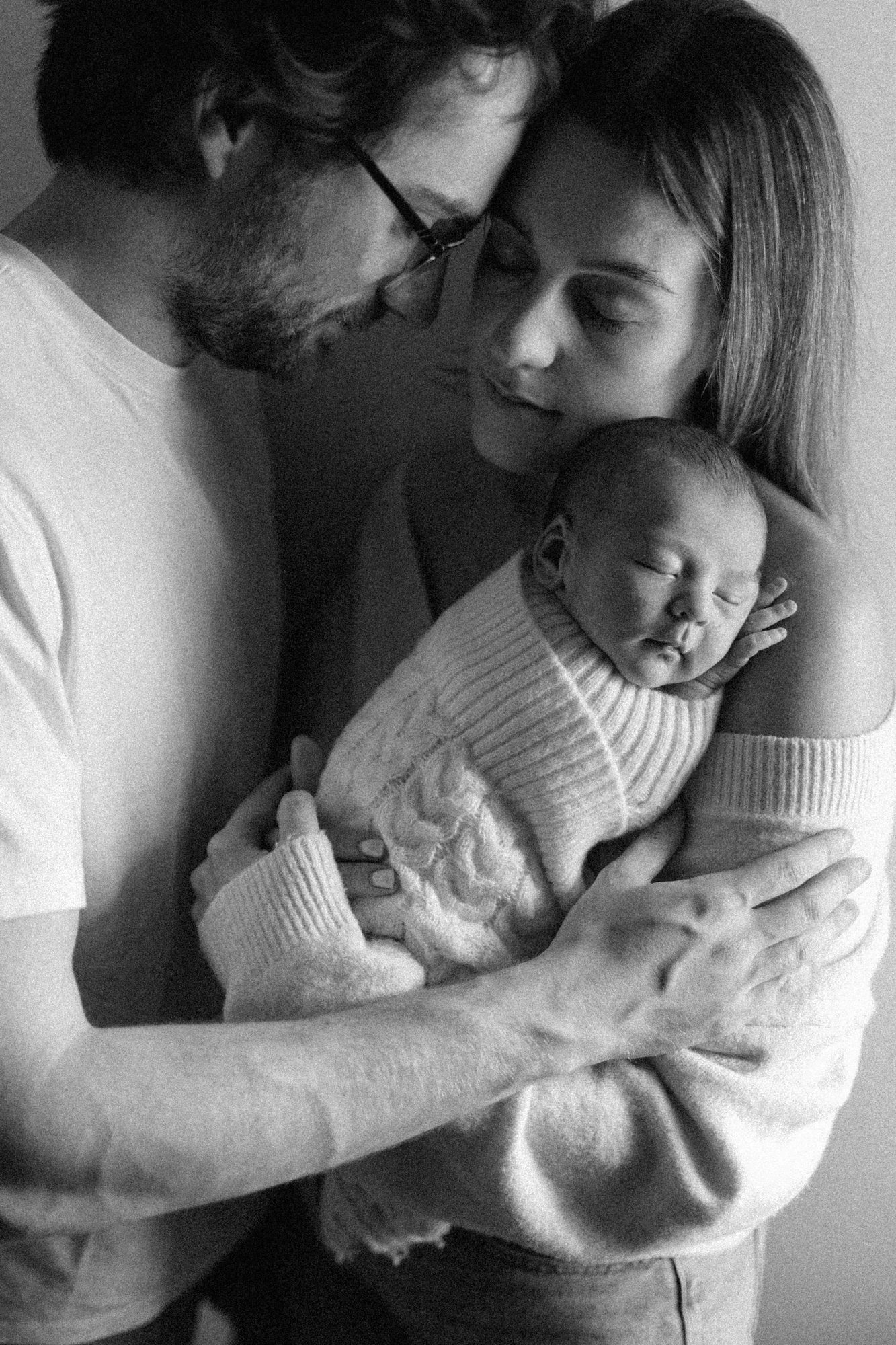 Photographie nouveau-né à Rimouski en noir et blanc : un couple portant leur bébé Théo-Charles, témoignant de l'authenticité.