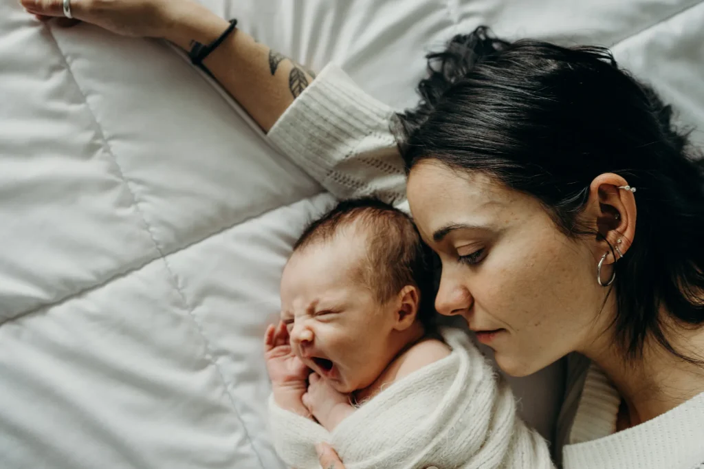 Une maman serre tendrement son nouveau-né contre elle, illustrant la douceur et l'aura de la naissance lors d'une séance photo à Rimouski.