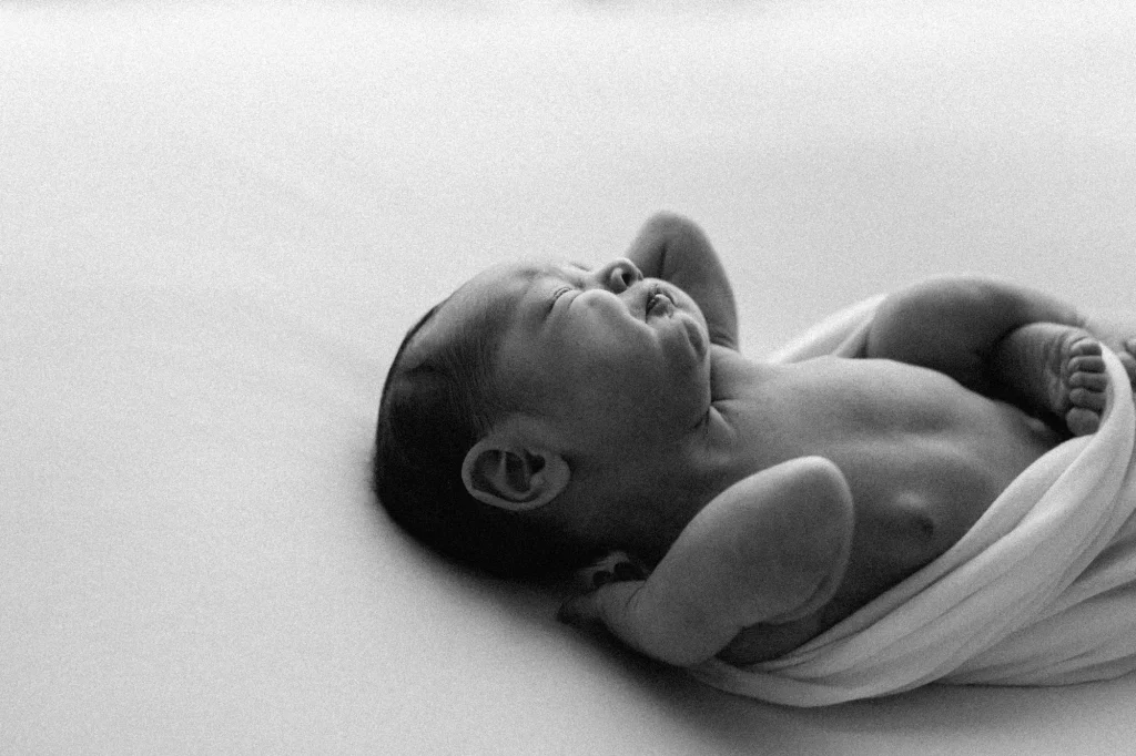 Image noir et blanc d'un nouveau-né qui s'étire capturé sur le vif par 5Mphotographie.