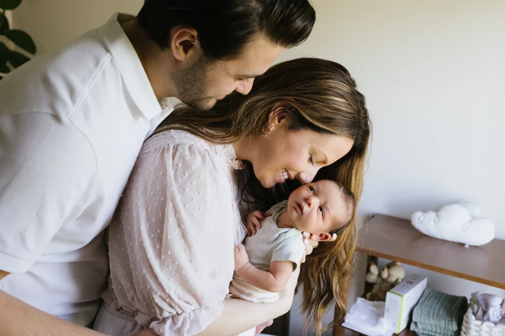 Un père et une mère tiennent leur enfant tendrement dans leur bras.