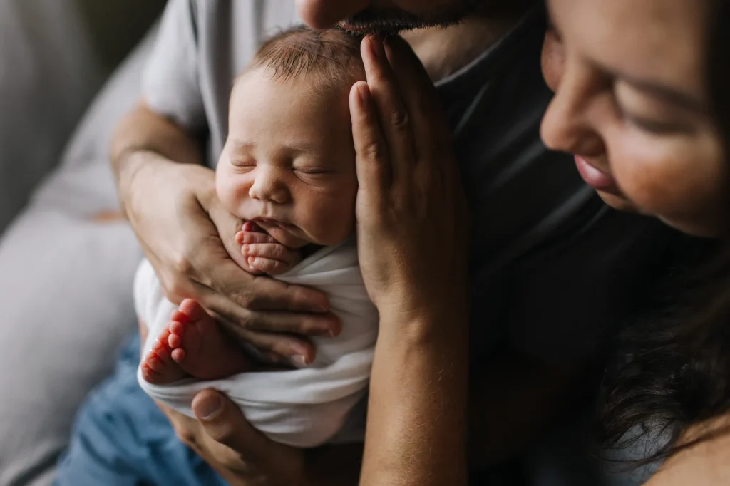 Moment d'intimité où les parents admirent leur nouveau-né emmailloté, une séance photo famille et nouveau-né réalisée à Rimouski.