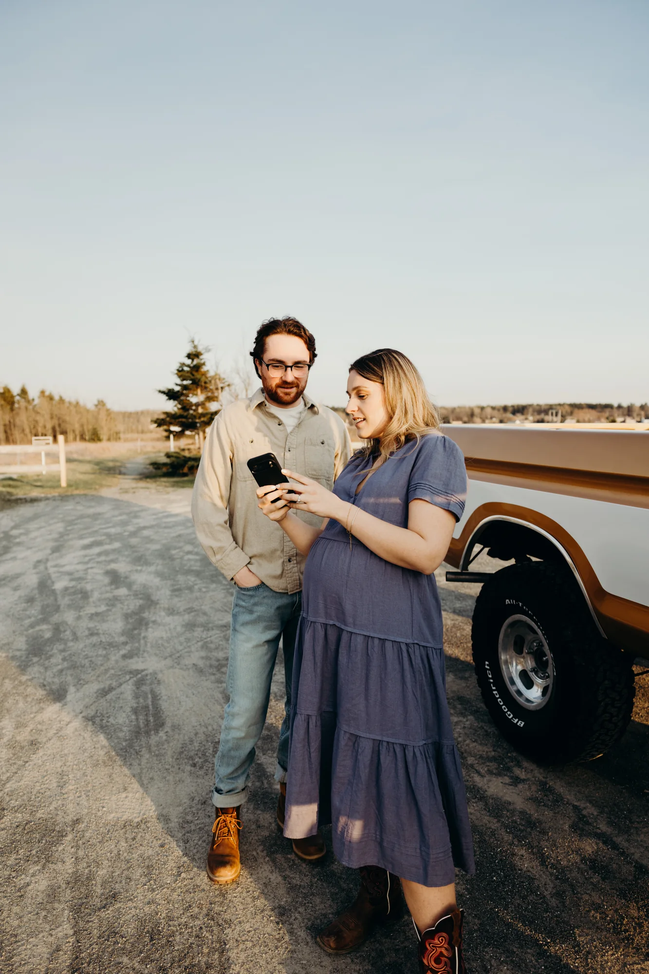 Femme enceinte avec une robe bleue montrer à son conjoint une image sur son cellulaire.
