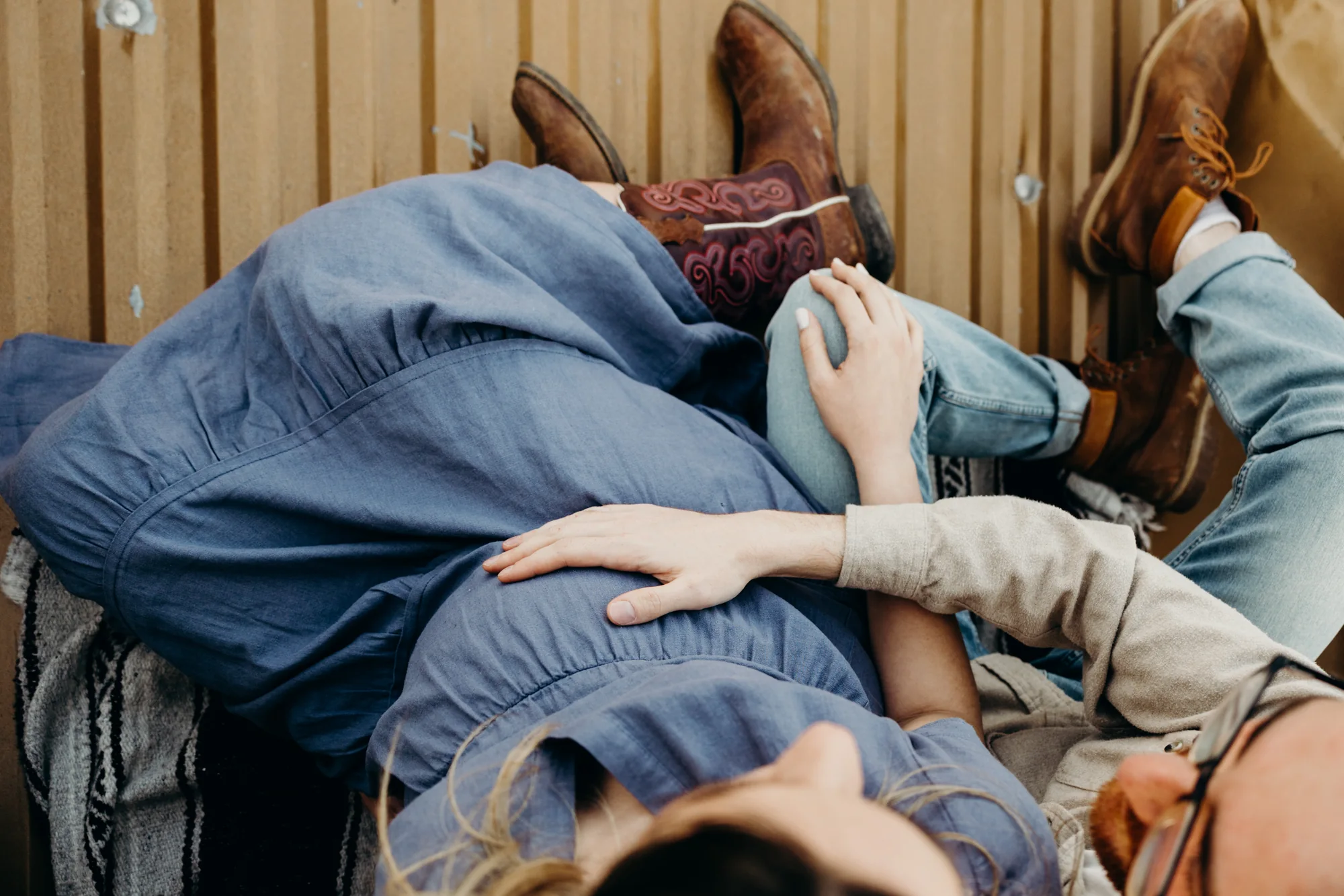 Vue de haut d'un homme qui met sa main sur le ventre rond de sa femme avec une robe bleue.
