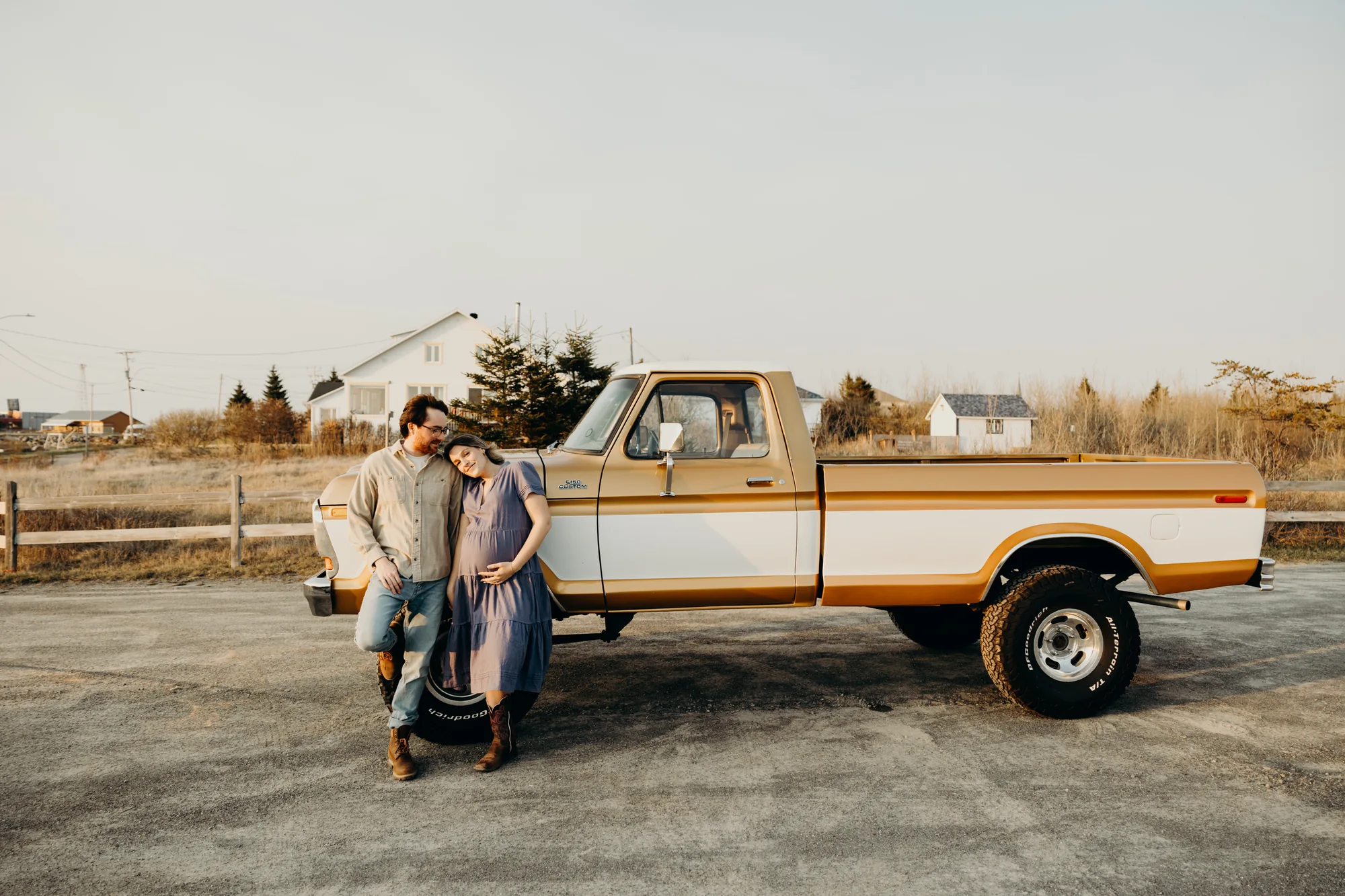 Futurs parents échangeant un regard complice devant leur camion antique brun et blanc.
