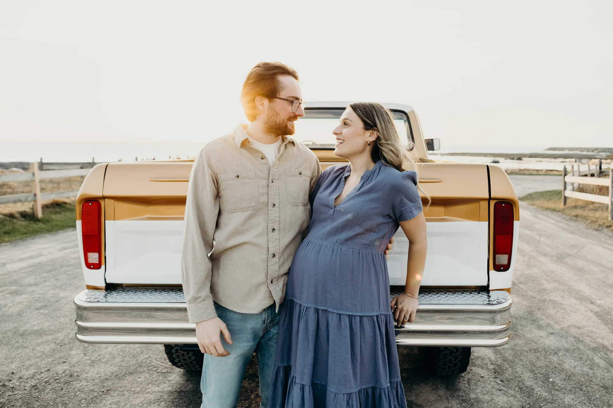 Futurs parents échangeant un regard complice devant leur camion beige et blanc.