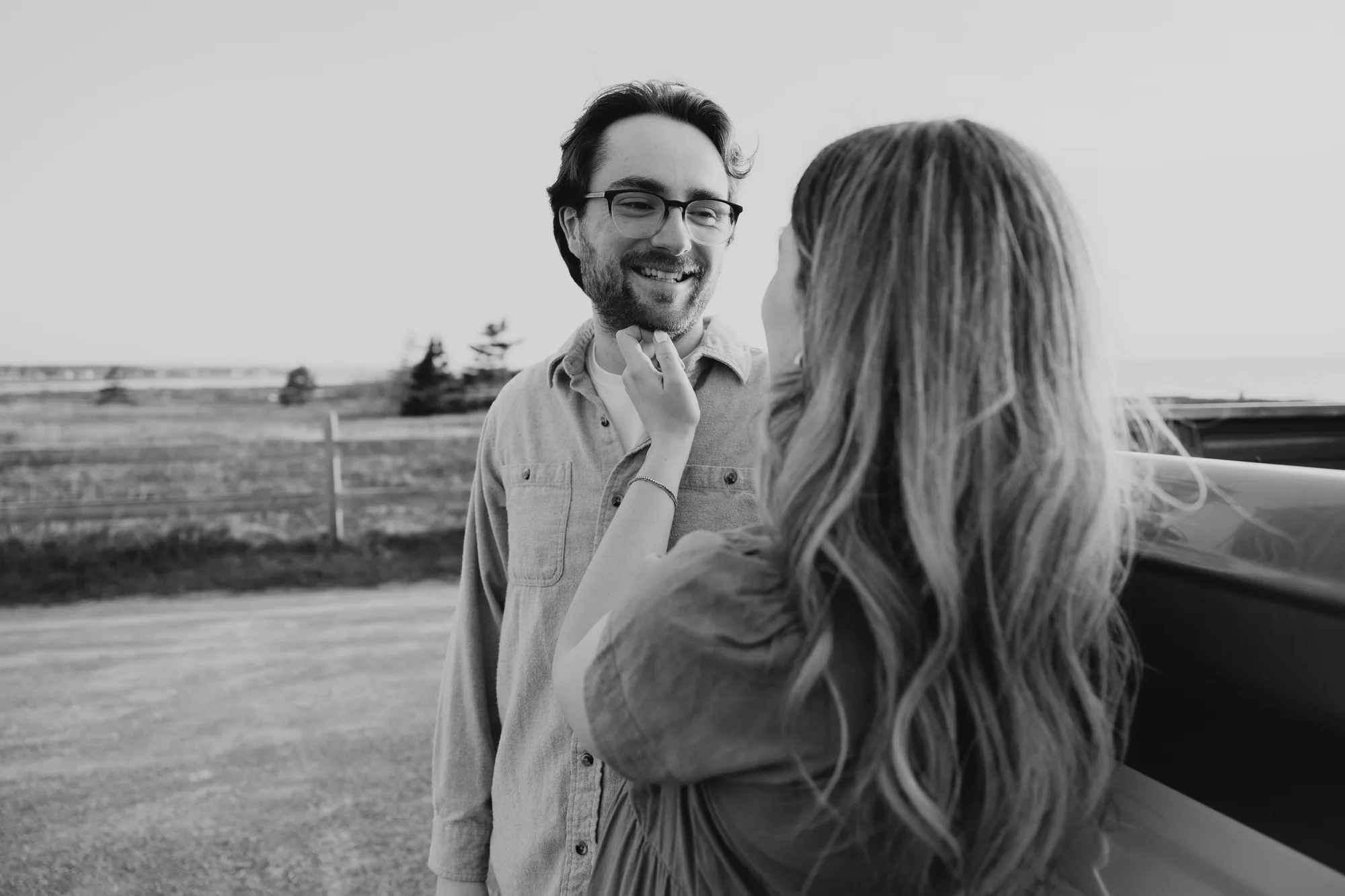 Femme enceinte qui regarde tendrement son conjoint en noir et blanc et lui tient le menton.