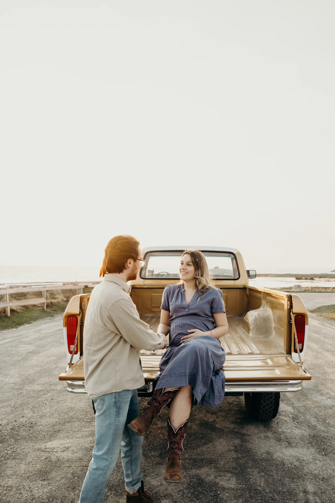 in de séance photo maternité avec le vieux pick-up sous un ciel doux.