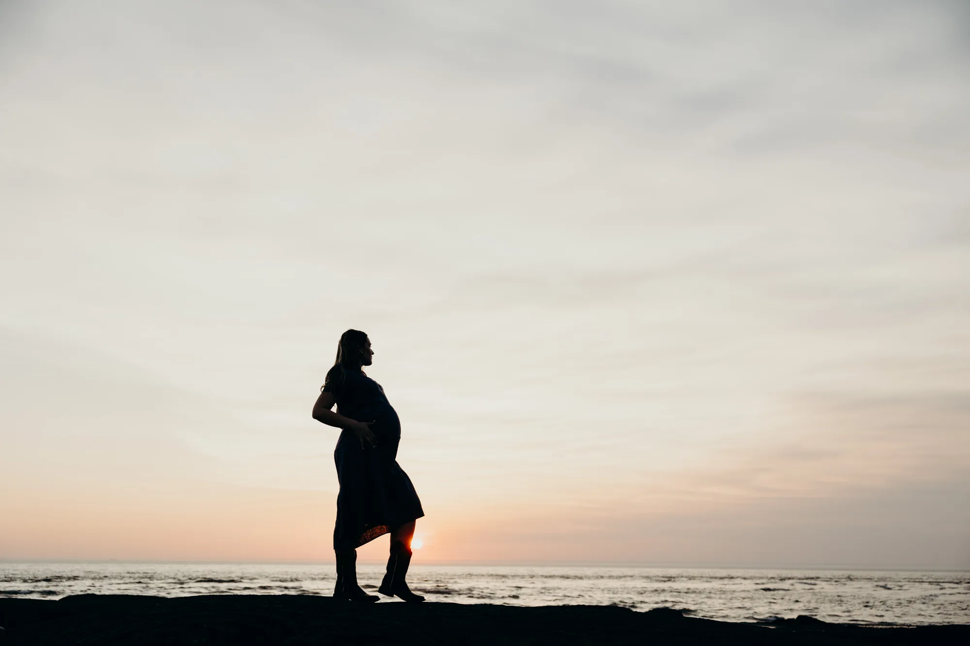 Portrait de la future maman mettant en valeur sa silhouette au coucher du soleil.
