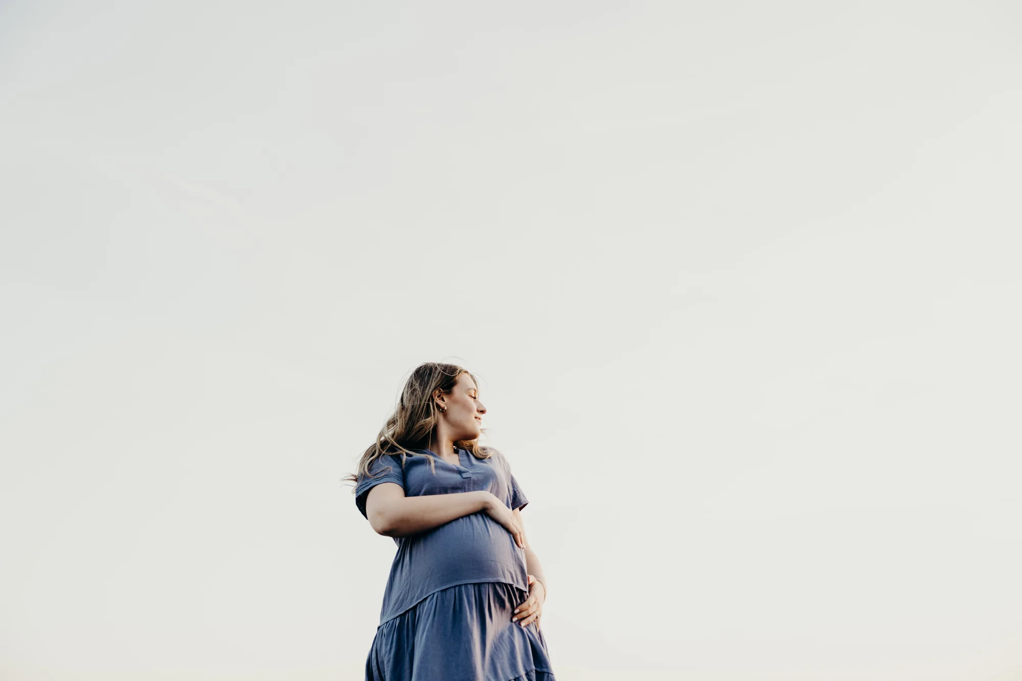 Portrait de la future maman mettant en valeur sa silhouette au coucher du soleil.